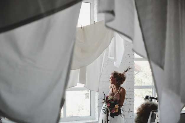 beautiful-woman-stands-with-bouquet-hanging-laundry-room_8353-7845-7854756