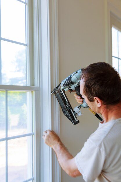 carpenter-using-nail-gun-moldings-windows-framing-trim_73110-4662-6018066