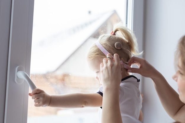 mother-helps-her-deaf-baby-daughter-putting-hearing-aid-little-girl-s-ear-indoors-cochlear-implant-innovative-medical-technologies-treatment-deafness_230311-40036-6904664